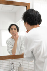洗面所で鏡を見る男性