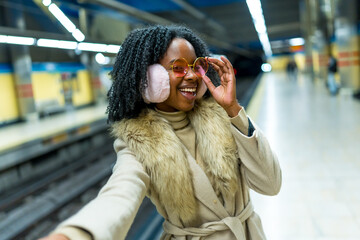 Young black woman taking selfie in subway station