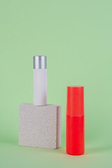 Cosmetic red bottle and hand, bottle, lotion or serum with stylish props on green background. 