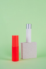 Cosmetic red bottle and hand, bottle, lotion or serum with stylish props on green background. 
