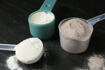 Protein powders in scoops on dark textured table
