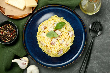 Plate with delicious pasta Carbonara, products and cutlery on grey textured table, flat lay
