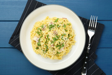 Delicious pasta Carbonara served on blue wooden table, flat lay