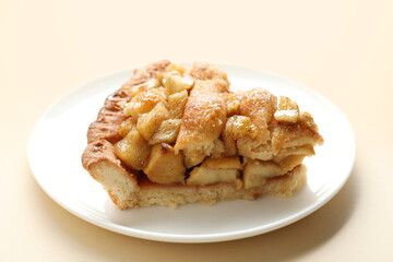 Slice of homemade apple pie on beige background, closeup