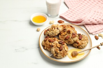 Tasty cookies with nuts and honey dipper on white marble table, closeup. Space for text