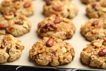 Tasty cookies with nuts on parchment paper, closeup
