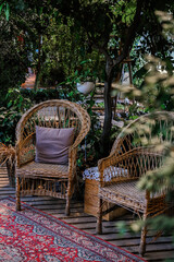 Obraz premium Cozy outdoor seating area with natural greenery and woven chairs in a tranquil garden setting