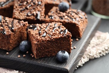 Delicious chocolate puffed rice bars and blueberries on gray table, closeup