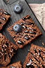 Delicious chocolate puffed rice bars and blueberries on table, top view