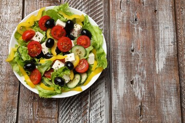 Delicious fresh Greek salad on wooden table, top view. Space for text