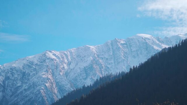 Clouds above the snowy Himalayan mountain peaks during a sunny day as seen from Triloknath village near Udaipur in Pattan Valley, Lahaul and Spiti district, Himachal Pradesh, India. Winter background.