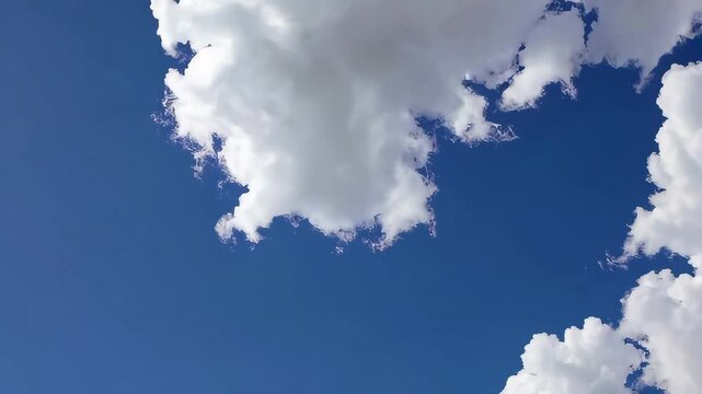 Timelapse of clouds moving across a blue sky with fluffy white clouds drifting across a clear background.

