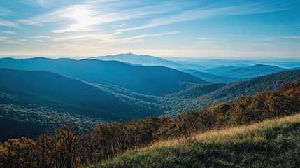 Fototapeta premium A breathtaking view of rolling mountains under a clear blue sky, showcasing lush green valleys and distant peaks bathed in soft sunlight.