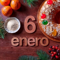 Letras 6 enero de madera acompañadas por un roscón de reyes, dulce típico del 6 de enero en España