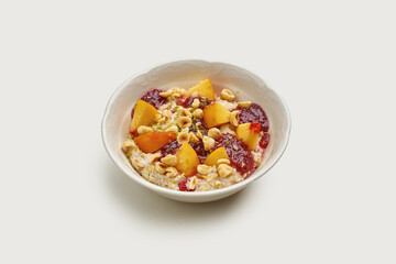A bowl of creamy oatmeal topped with fresh fruit, crunchy nuts, and a drizzle of sweet jam.