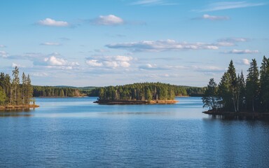 Fototapeta premium Masurian Lake District Serenity, Poland Calm lake with small wooded islands under a blue sky.