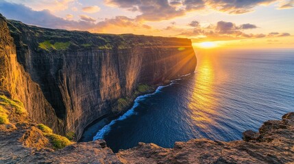 Majestic cliff view at sunset, with golden light illuminating the rugged terrain and the vast sea below.