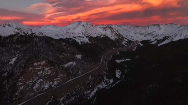 Rocky Mountains aerial drone i70 highway Winter solstice Colorado vibrant orange red cloudy skies setting sunset cars trucks traffic Coon Hill Parshall Eisenhower tunnel Continental Divide forward pan