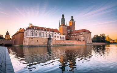 Obraz premium Krakow's Wawel Castle, Poland Majestic castle reflected in calm waters at sunrise.