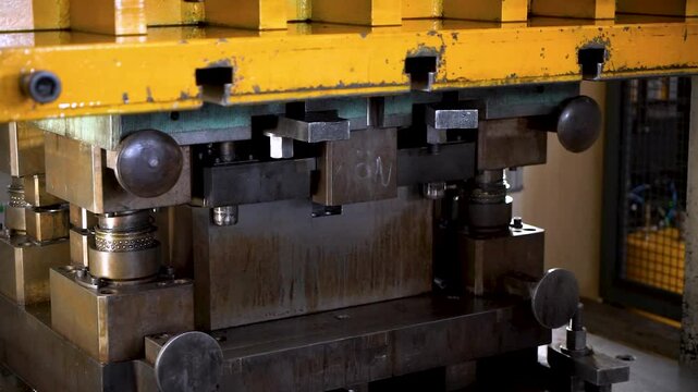 Close up view of a large hydraulic transfer press line shaping metal parts in a factory.