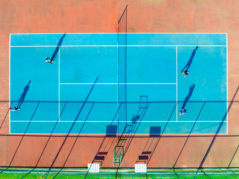 Aerial View of Tennis Players on a Vibrant Blue Court During a Sunny Day