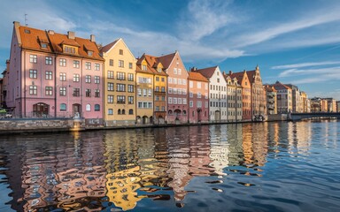 Gdansk Waterfront, Poland Colorful houses reflected in calm river water under a blue sky.