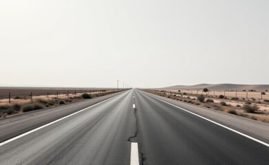 Fototapeta premium A scenic road winds through a dramatic desert landscape, with towering red rock cliffs and a clear blue sky in the background.