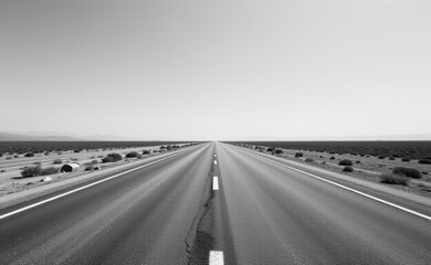A scenic road winds through a dramatic desert landscape, with towering red rock cliffs and a clear blue sky in the background.