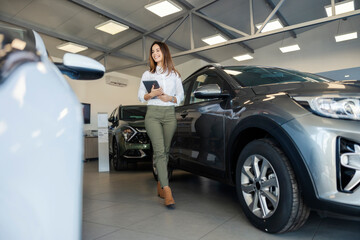 Full length of professional car seller walking around luxury car showroom.