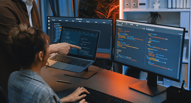 Serious of IT developers discussing intelligent website development coder system running data online two screens with laptop showing information network at neon light room at modern office. Infobahn.