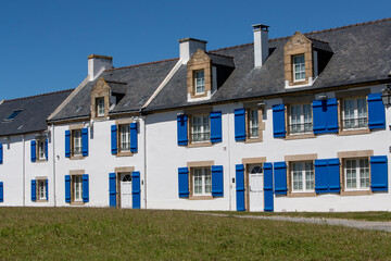 Vue sur le bâtiment au centre du village de l'îlot Saint-Cado en Bretagne, France. Façade blanche et volets bleus foncés.