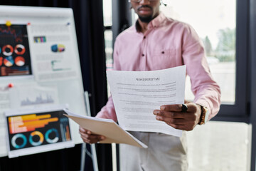 Young african american man reviewing documents in a bright office space while working remotely