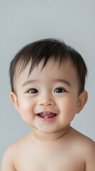 Adorable portrait of smiling South East Asian baby boy with joyful expression on clean backdrop
