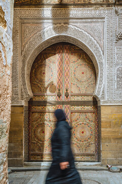 Woman walking by old doorway in the Medina, Fes, Morocco