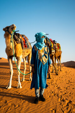 Berber man with tunic and camels in the desert, Erg Chebbi, Morocco