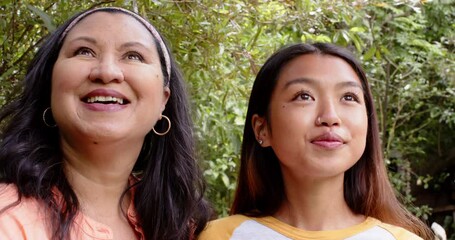 Laughing together in garden, multiracial grandmother and young woman