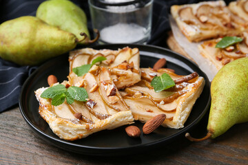 Pieces of tasty puff pastry pie with pears, mint and almonds on wooden table, closeup