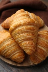 Tasty fresh croissants on wooden table, closeup. Puff pastry