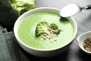 Delicious broccoli cream soup served on black table, closeup