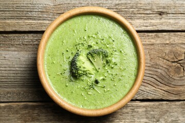 Delicious broccoli cream soup in bowl on wooden table, top view