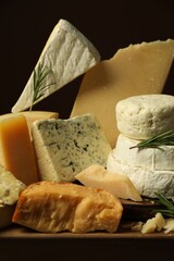 Different types of cheese and rosemary on table, closeup