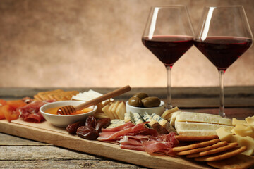 Different types of delicious cheese, other snacks and wine on wooden table, closeup