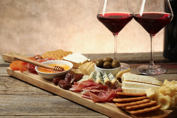 Different types of delicious cheese, other snacks and wine on wooden table, closeup