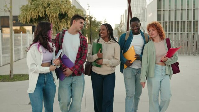 Cheerful young multiethnic college students talking and walking after classes on University campus 