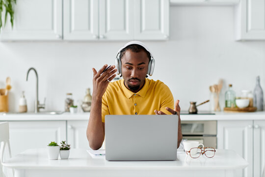 Young african american man working remotely in a bright kitchen communicating online