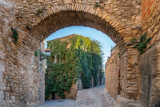 Medieval Archway Framing an Ivy-Covered Building. Scenic Street in Peratallada, Spain - Medieval Village in the Emporda - Powered by Adobe