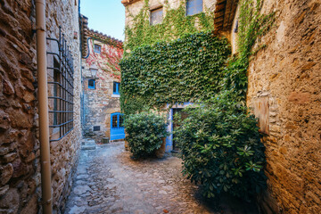 Fototapeta premium Rustic Stone House Covered with Green Ivy. Traditional Mediterranean Architecture in a Picturesque Village. Peratallada is a town on the Costa Brava, in northern Spain, Catalonia.