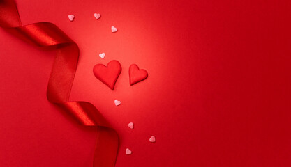 Red ribbon and small red hearts on red background. Happy Valentines day, Mothers day, birthday, wedding concept. Romantic flat lay.