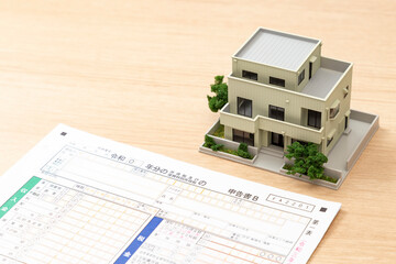 机に置かれた確定申告書類と住宅模型