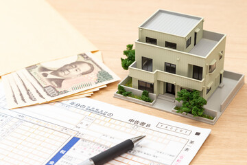 机に置かれた確定申告書類と住宅模型